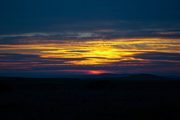 Atardecer de colores intensos amarillo y naranja con siluetas de horizonte