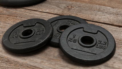 Three dumbbell discs for weight lifting on wooden floor