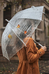 Faceless woman holding umbrella outdoors in autumn park during rain. Selective focus
