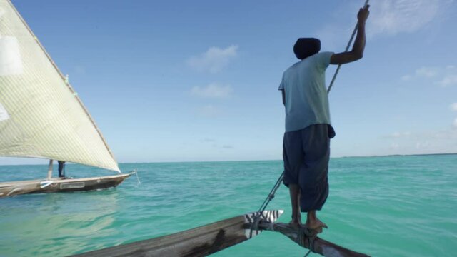 Outrigger sailing dhow travelling off the coast of Zanzibar. Tanzania. Africa.