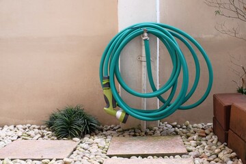 watering hose hanging on faucet in garden