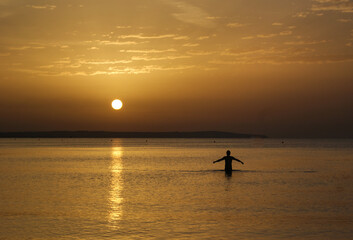 Minimalist silhouette composition of man standing in the sea during the sunrise or sunset
