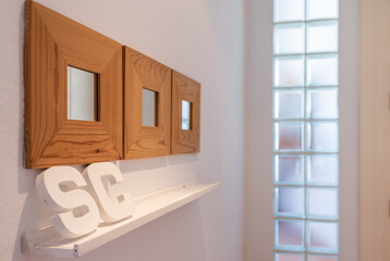 Detail photo, small mirrors with wooden frames, white wooden shelves with large wooden letters SC, in the background a glass skylight