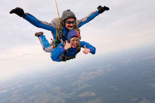 Skydiving. Tandem jump. A girl and her instructor are flying in the sky.