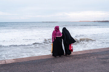 Kobiety, muzułmanki w burkach nad brzegiem oceanu.