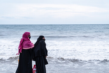 Kobiety, muzułmanki w burkach nad brzegiem oceanu.