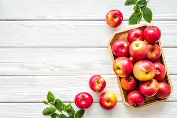 Group of red apples in wooden tray with leaves. Autumn harvest