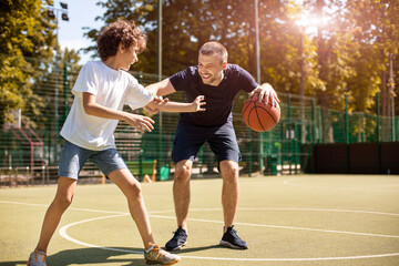 Obraz premium Mature man teaching boy how to play basketball