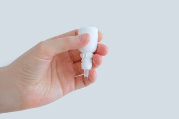 Eye drops in white bottle close-up in a hand. White background.
