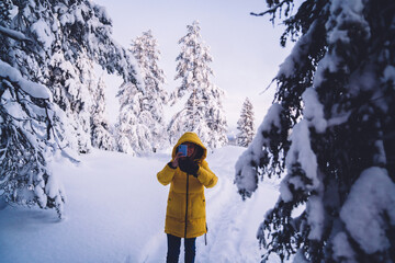 Cheerful caucasian female in winter coat standing on wild northern environment explore destination making pictures on smartphone, happy woman travel blogger using camera on mobile phone