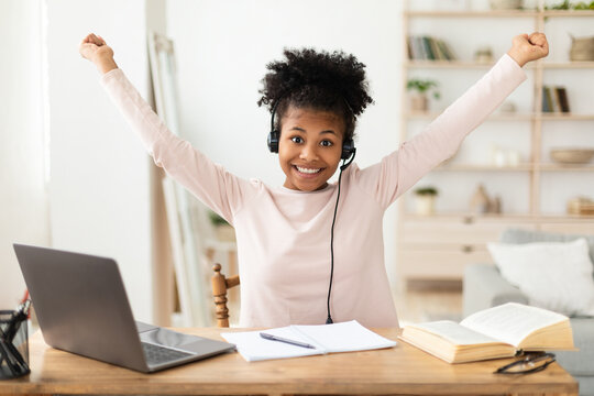 Joyful African American Girl At Laptop Raising Hands At Home