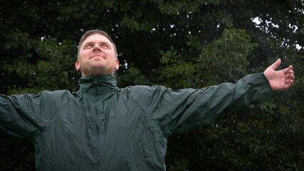Portrait of a man smiling happy in the rain and breathing air of freedom, dreams, and love for nature. Concept of: lifestyle, nature, freedom, rain and happiness.