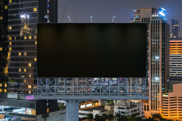 Blank black road billboard with Bangkok cityscape background at night time. Street advertising poster, mock up, 3D rendering. Front view. The concept of marketing communication to sell idea.