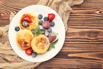 Sweet cheese pancakes with berries and mint leafs on wooden table
