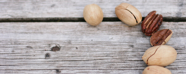 Obraz premium Pecan Nuts on wooden background, top view with copyspace. Close up veiw of nuts. Banner size with copy space. 