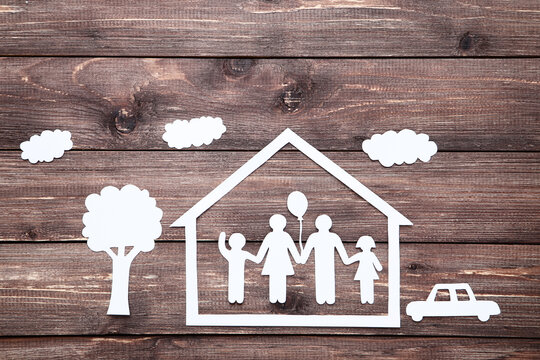 Paper family figures with tree and house on brown wooden table