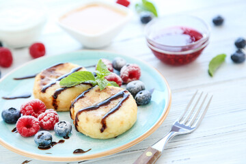 Sweet cheese pancakes with berries and fork on wooden table