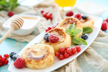 Sweet cheese pancakes with berries and mint leafs on blue background