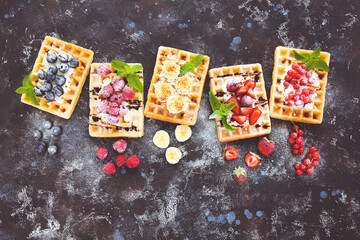 Tasty waffles with fresh berries and whipped cream on black background