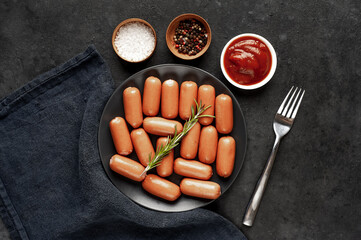 raw mini sausage plate with spices and ketchup on a stone background