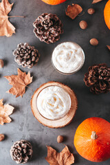 Autumn background with natural pine cones, pumpkins, dried leaves and pumpkin latte on dark grey stone top, top view, copy space. Fall, Thanksgiving background, cozy flat lay
