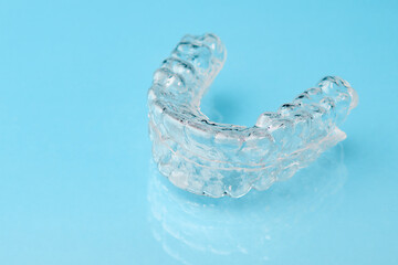 Close up invisible aligners on the blue background with copy space. Plastic braces dentistry retainers to straighten teeth.
