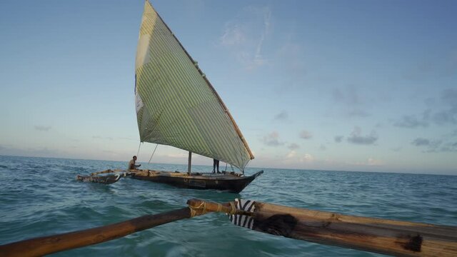 Outrigger sailing dhow travelling off the coast of Zanzibar. Tanzania. Africa.