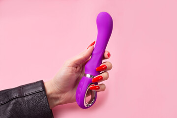 Dildo in hand on a pink background, sex toy