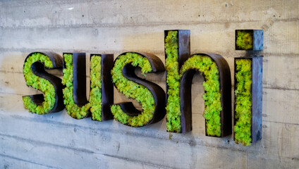 lettering word sushi from old rusty iron and green grass on wooden background