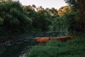 Obraz premium Calm water flow, morning fog and wooden boat. Summer or autumn sunrise over the river. Natural beauty of pristine nature. Water protection zone. Beautiful landscape banner. Card