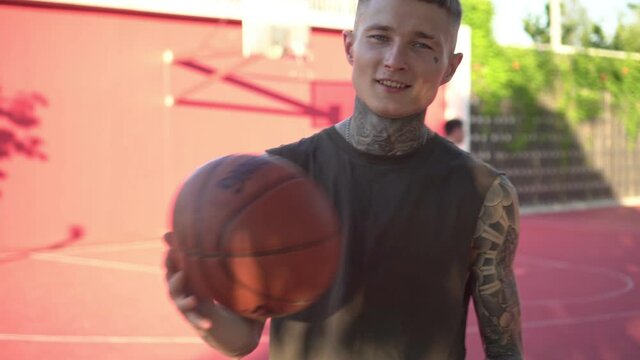 Portrait of a young modern man with tattoos on a street basketball court. Modern youth image