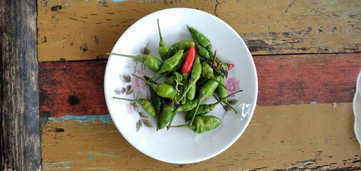Bird's eye chilies on a white plate. On an aestethic wooden table background. Flat lay photos