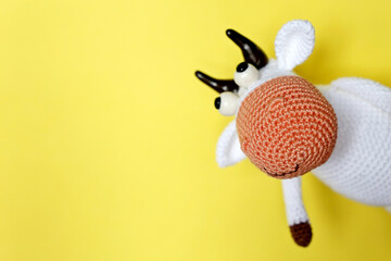 White knitted toy bull on yellow background, New Year greeting card with free copy space for text. Chinese Year of Bull, Zodiac symbol 2021
