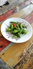 Bird's eye chilies on a white plate. On an aestethic wooden table background. Flat lay photos