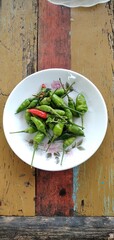 Bird's eye chilies on a white plate. On an aestethic wooden table background. Flat lay photos