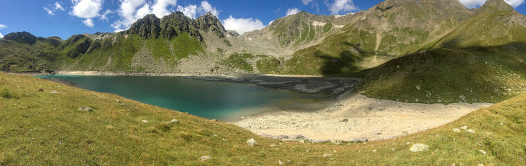 Panoramic view of an alpine lake between the rocks.