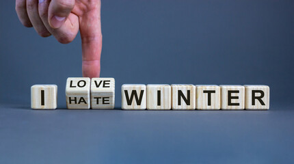 Hand turns cubes and changes the expression 'I hate winter' to 'I love winter'. Beautiful grey background, copy space. Concept.