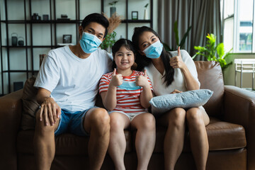 Asian family spending time together at home while wearing face mask. precaution to prevent coronavirus by wearing protective mask.