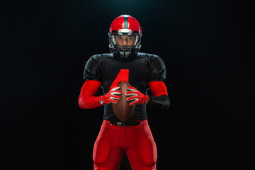 American football player, athlete sportsman in red helmet on black background. Sport and motivation...