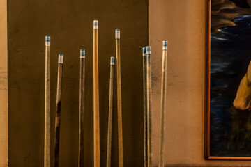 A group of billiard cue sticks near a wall.