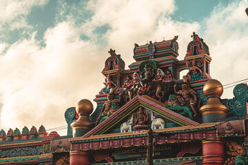 Hindu temple full of colorful ornaments against a blue sky on a sunny day.
