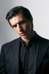 Frontal portrait of a business man dressed in black suit against a dark background.