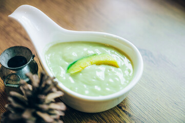 Fresh avocado smoothie with slices on wooden background