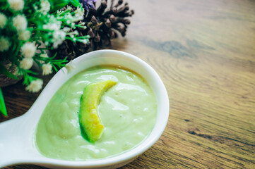 Fresh avocado smoothie with slices on wooden background