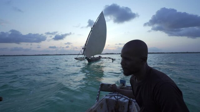 Outrigger sailing dhow travelling off the coast of Zanzibar. Tanzania. Africa.