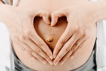 A Young beautiful Asian woman standing in bedroom. mom is love to holding her big belly with two hands. isolated and white background  picture with film grain effect