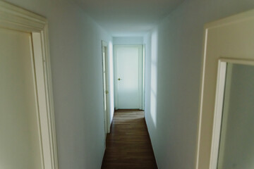Narrow hallway with a spooky looking closed white door