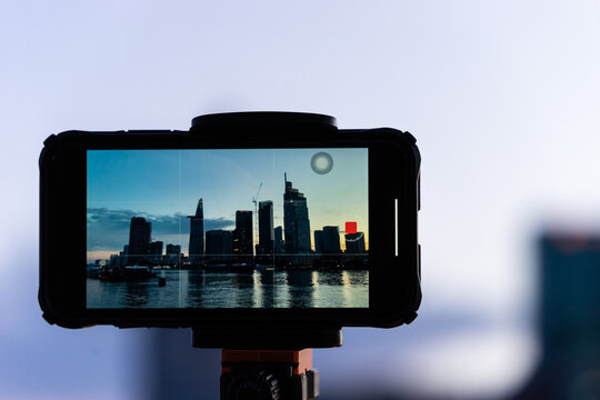 A phone on tripod recording the beautiful landscape sunset of Ho Chi Minh city or Sai Gon, Vietnam with many skyscraper buildings