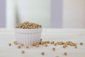 The soybeans are in the white cup placed on the wooden table.