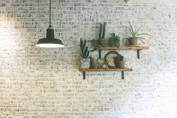 Modern stylish white brick wall with shelves and plants. Hanging lighting lamp giving creating...